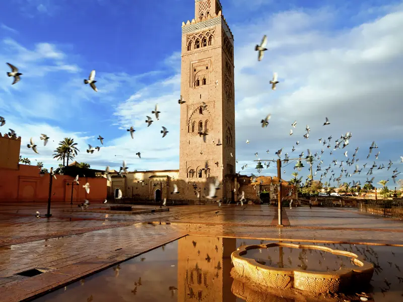 Über Silvester mit anderen Singles und Alleinreisenden nach Marrakesch: Das Minarett der Koutoubia-Moschee, Wahrzeichen der Königsstadt am Fuße des Hohen Atlas, ragt weithin sichtbar in den blauen Himmel.