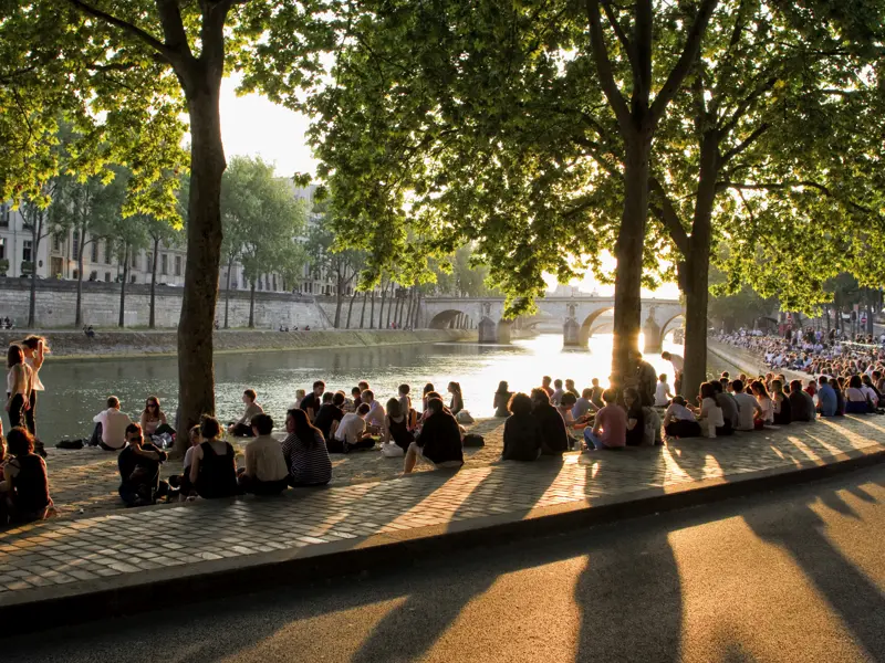 Paris, eine Stadt der Flaneure und Genießer! Auf unserer Städtereise zeigt uns die Studiosus-Reiseleiterin bzw. der Studiosus-Reiseleiter jede Menge bekannter und auch unbekannter romantischer Winkel in Paris. An einem schönen Sommerabend versammeln sich viele Pariser und Pariserinnen an den Ufern der Seine, um den Sonnenuntergang und die Stimmung in der Stadt zu genießen.