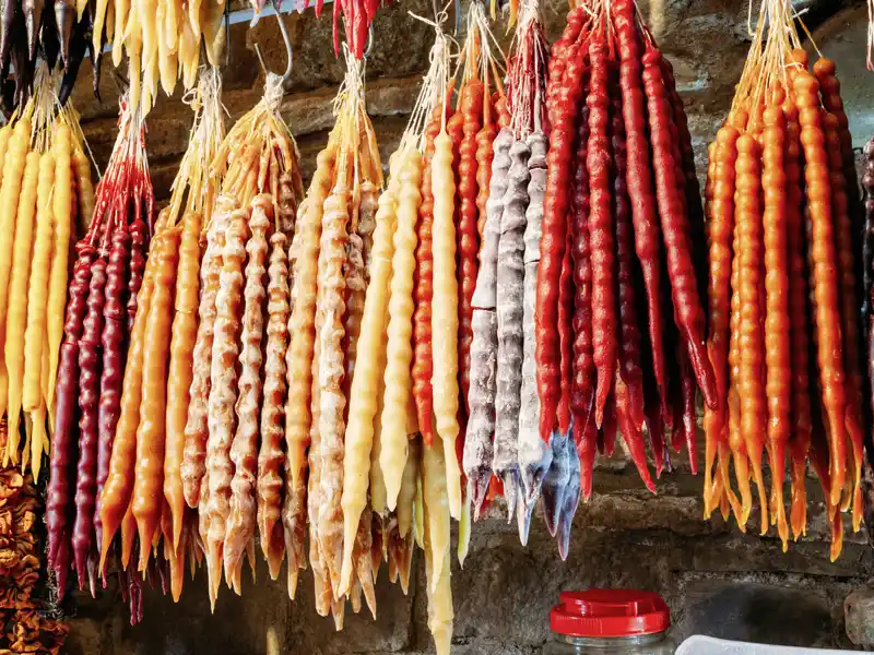 Auf unserer Silvesterreise für Singles und Alleinreisende durch Georgien kosten wir Tschurtschchela, das typische georgische Konfekt, das traditionell als Dessert gegessen wird. Dabei handelt es sich um Wal- oder Haselnüsse, die mit einer Traubensaft-Kuvertüre überzogen sind.