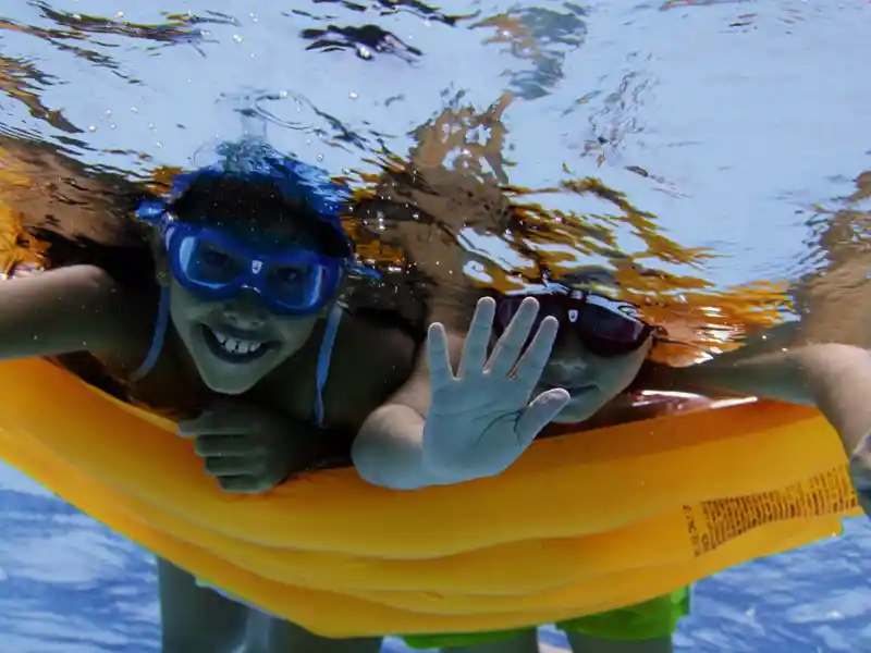 Auf der Familien-Studienreise nach Griechenland haben die Kinder wie hier beim Schwimmen und Tauchen auf einer Luftmatratze im Meer viel Spaß.