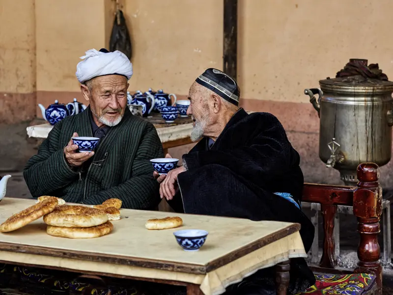 Auf unserer Studienreise Usbekistan - Höhepunkte treffen wir immer wieder Einheimische. Die blauen Teeschälchen mit Baumwollmuster sind typisch für Usbekistan, die kreisrunden Fladenbrote ebenso.