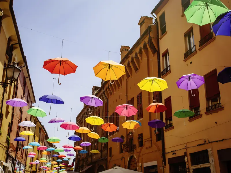 Auf unserer klassischen zehntägigen Studienreise nach Bologna brauchen wir eher keine Regenschirme. Deshalb können sie praktisch über der Straße als kunstvoller Sonnenschutz dienen.