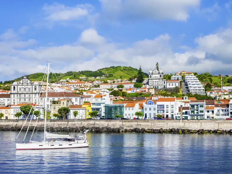 Hafenstadt Horta auf der Azoreninsel Faial mit traditioneller Architektur und einem Segelboot.
