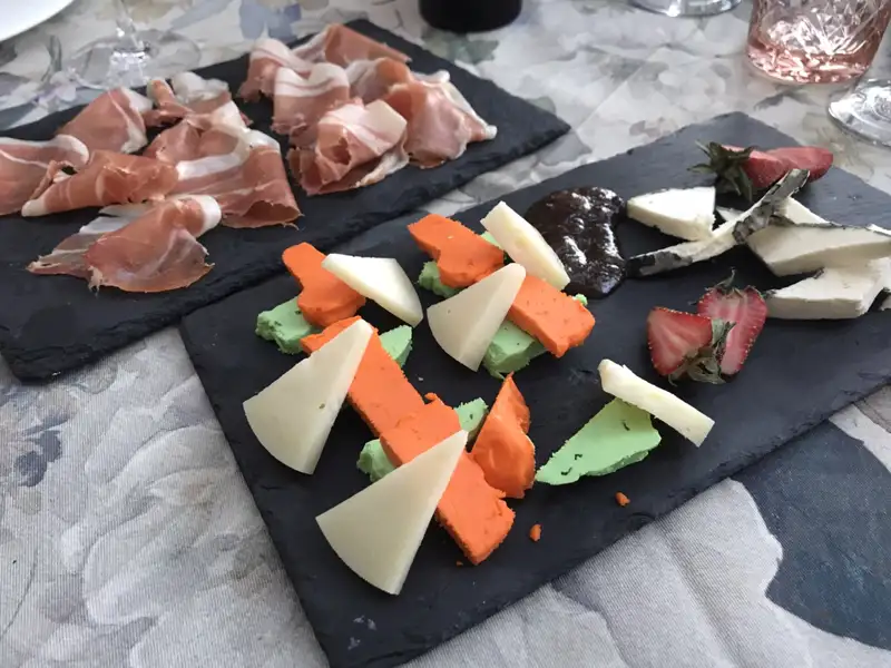 Eine Platte mit verschiedenen Käsesorten, Schinken und Erdbeeren.