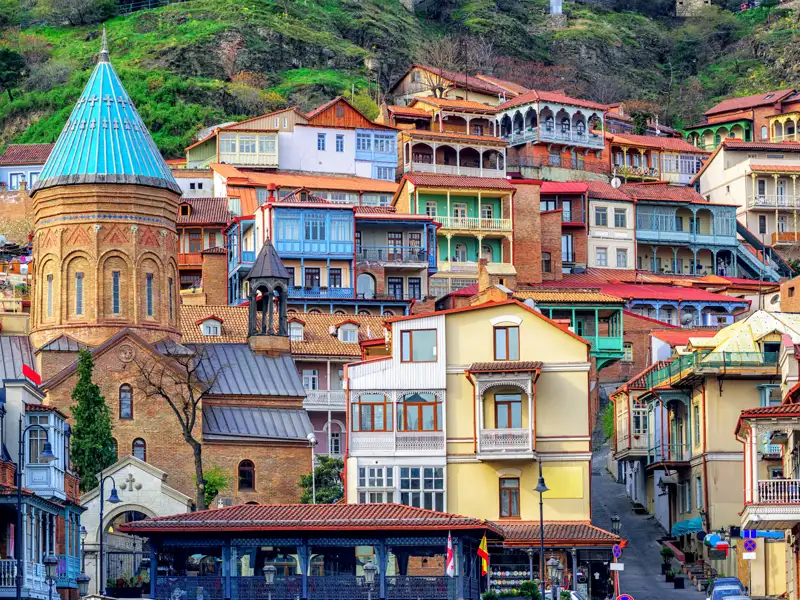 Traditionelle bunte Häuser mit Balkonen und eine Kirche in Tiflis, Georgien.