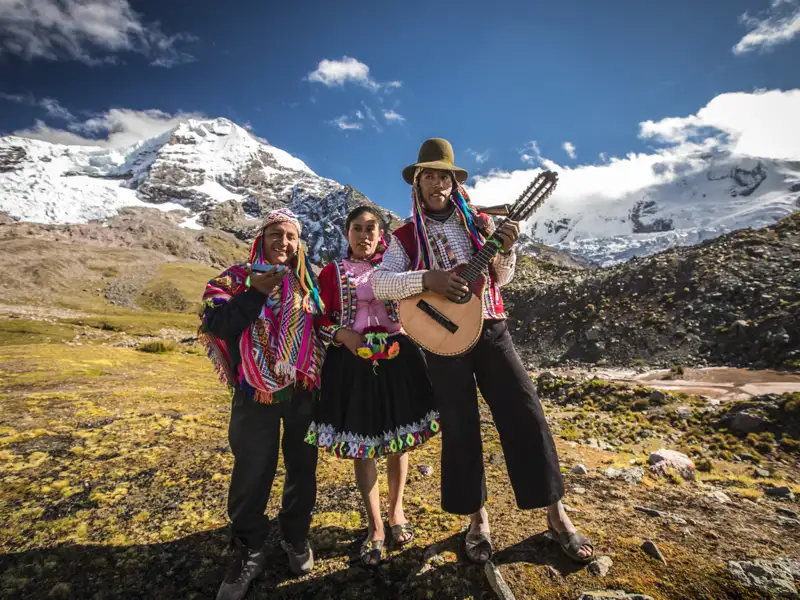 Einheimische Musiker in traditioneller Kleidung spielen vor der Kulisse der Anden.
