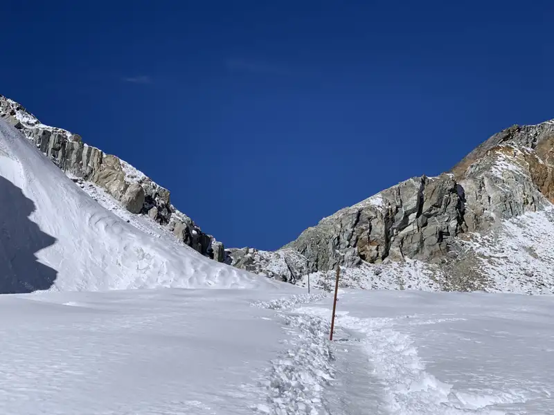 Verschneiter Bergpfad mit Markierungen.