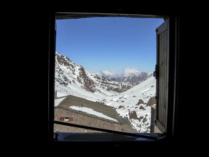 Blick aus dem Fenster auf eine verschneite Bergkette.