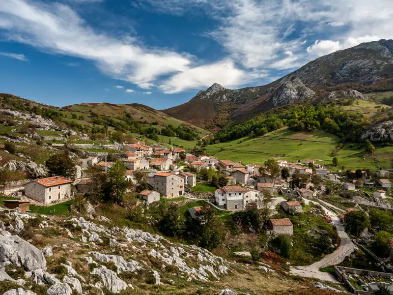 Blick auf ein Bergdorf mit traditionellen Häusern, umgeben von einer bergigen Landschaft.
