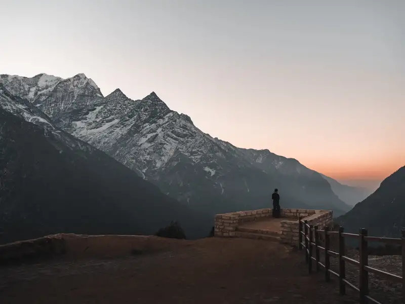 Aussichtspunkt mit Blick auf schneebedeckte Berge und Täler im Morgengrauen.