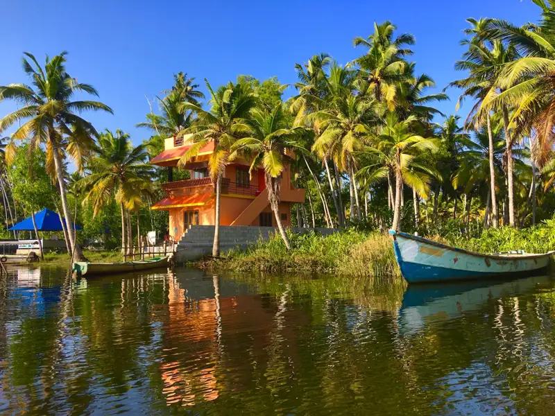 Haus am Wasser mit Palmen und Booten.