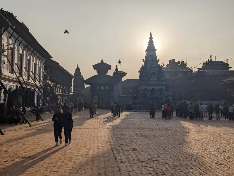 Tempel und Gebäude auf einem Platz bei Sonnenaufgang.