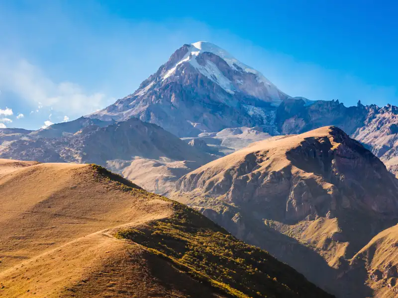 Die Swetizchoweli-Kathedrale in Mzcheta, Georgien. Die alten Steinmauern der Kathedrale erheben sich hinter einem Verkaufsstand mit bunten Tüchern.