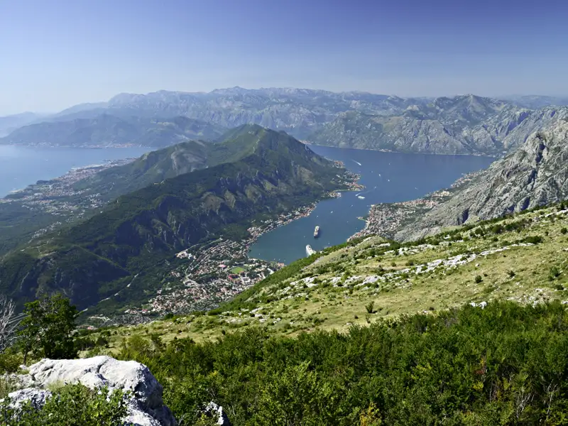 Aussicht auf die Bucht von Kotor von einem erhöhten Standpunkt aus.  Die Landschaft zeigt die Berge, das Wasser und die Küstenstädte.