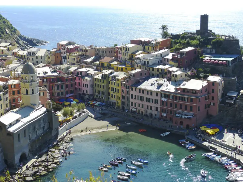 Luftbild von Vernazza, einem der fünf Dörfer der Cinque Terre in Italien. Bunte Häuser säumen den Hafen mit Booten im Vordergrund.