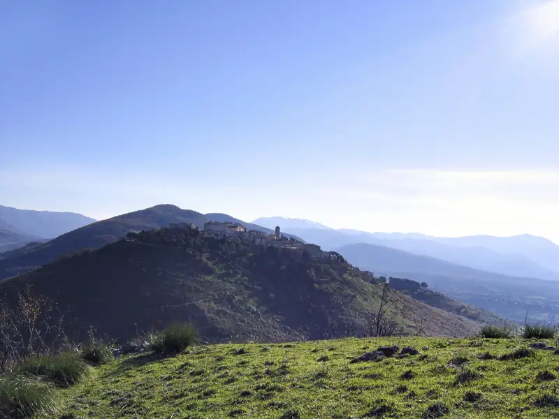 Panoramablick auf ein italienisches Bergdorf, umgeben von Hügeln und Bergen.