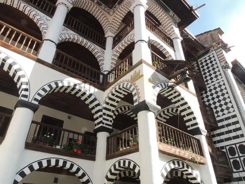 Schwarz-weiß gestreifte Bögen und Balkone eines Klosters.