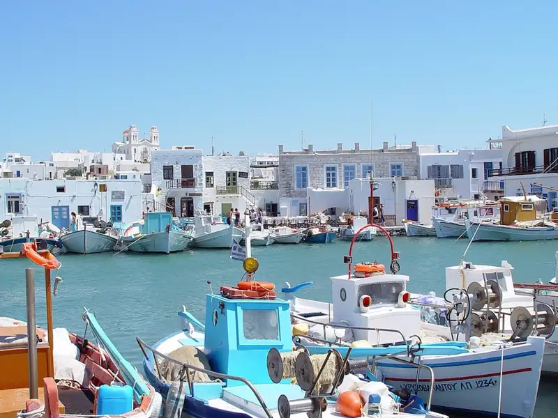 Fischerboote und weiße Häuser im Hafen einer griechischen Insel.