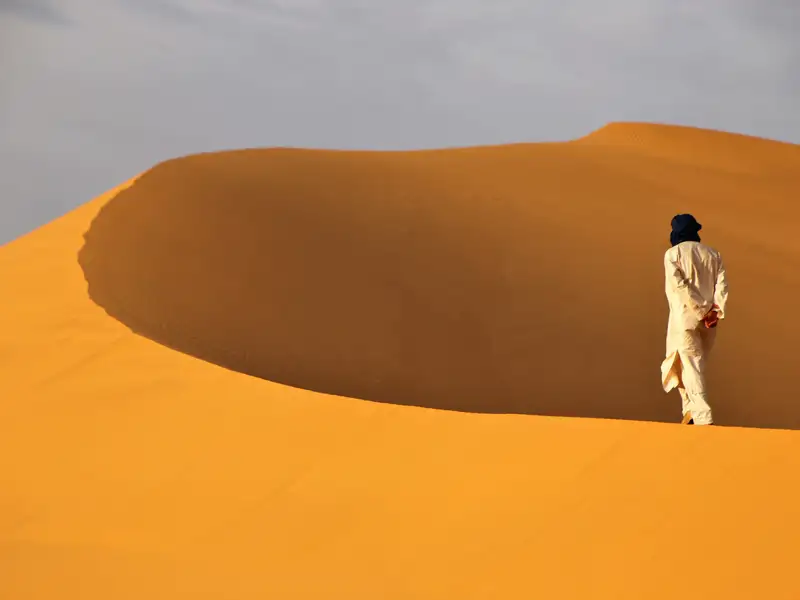 Person in traditioneller Kleidung in einer Wüstenlandschaft.