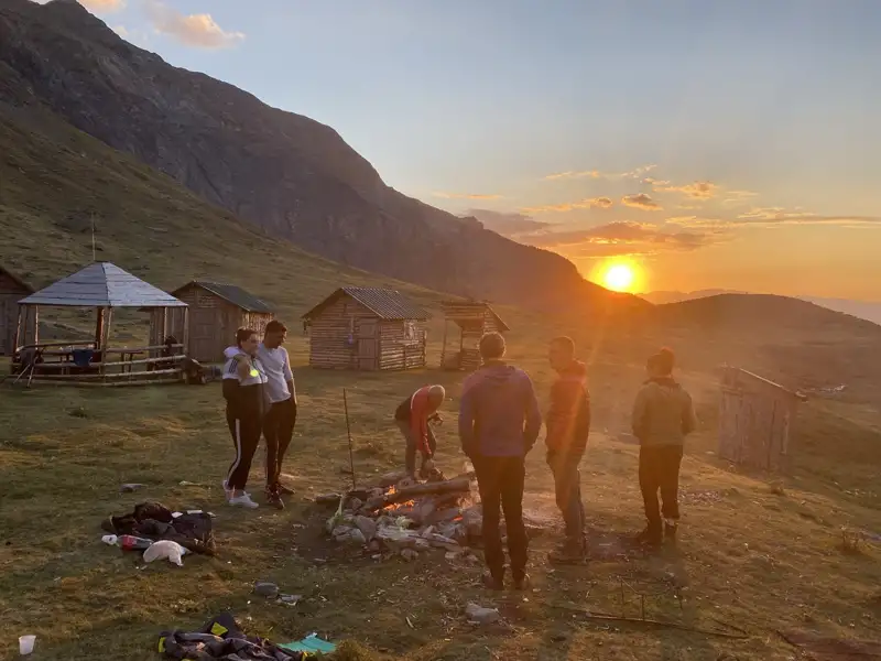 Wanderer am Lagerfeuer bei Sonnenuntergang in den Bergen.