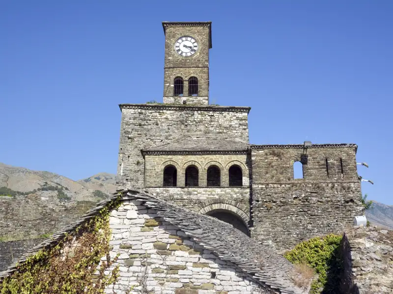 Uhrenturm und Steinmauern einer historischen Stätte.