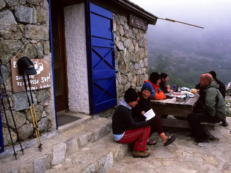 Wanderer pausieren an einer Berghütte und erfrischen sich.