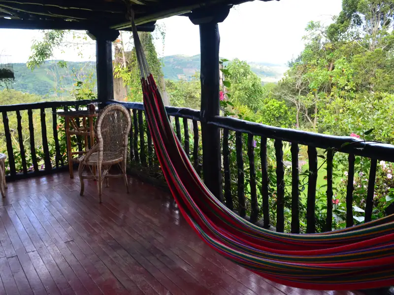 Hängematte auf einer Veranda mit Blick auf bewaldete Hügel.