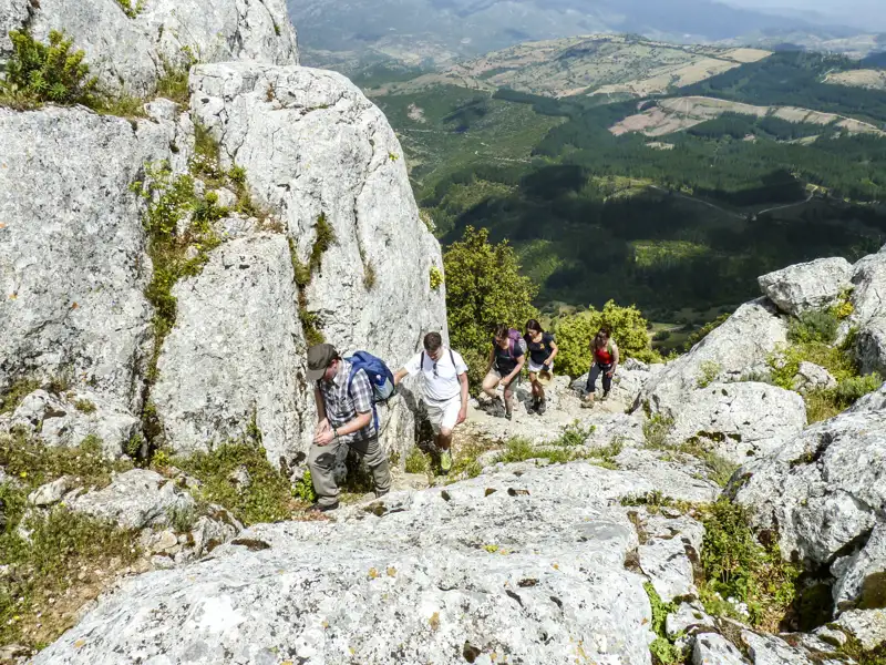 Wanderer bewältigen einen anspruchsvollen, felsigen Aufstieg im Gebirge.
