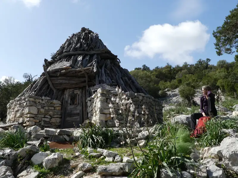 Wanderer macht Pause an einer traditionellen Hütte im Gebirge.