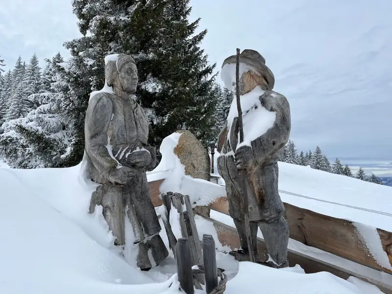 Zwei Holzfiguren, bedeckt mit Schnee, am Aussichtspunkt.