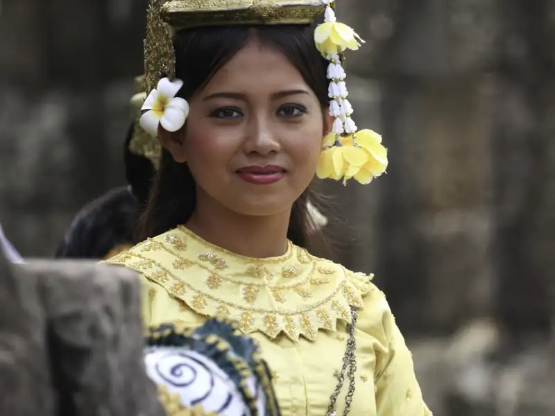 Eine Frau in traditioneller Kleidung, die goldene Verzierungen und Blumen im Haar trägt.