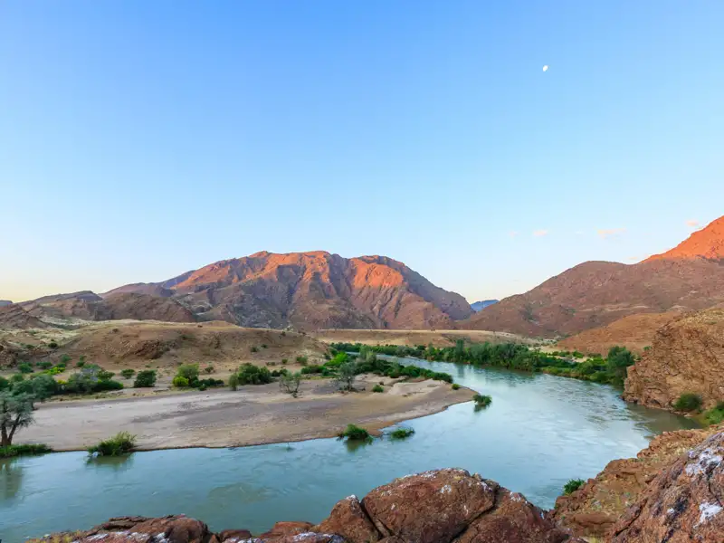 Panoramablick auf einen Fluss, der sich durch eine bergige Landschaft schlängelt.