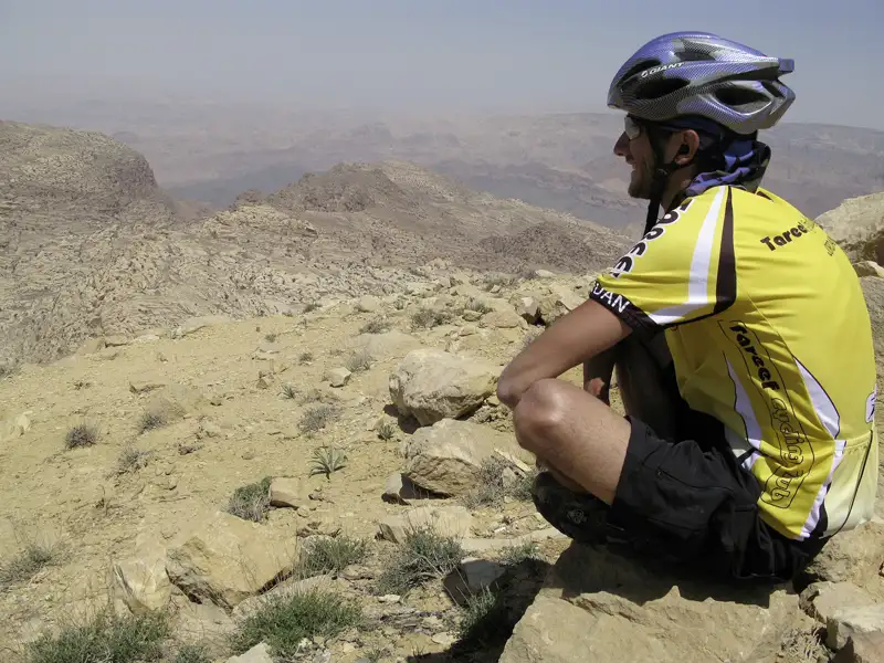 Radfahrer macht Pause in einer felsigen Wüstenlandschaft.