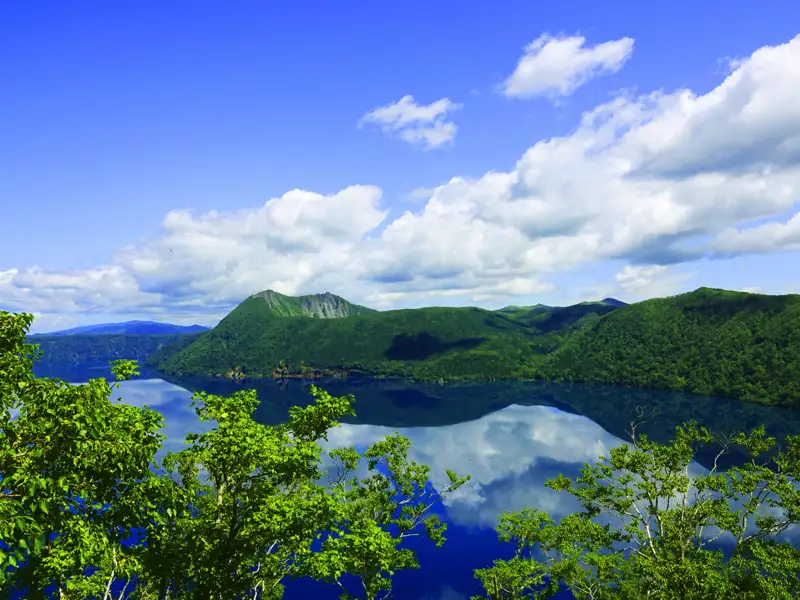 Panoramablick auf einen ruhigen See und grüne Hügel.