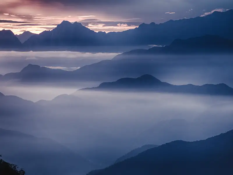 Sonnenaufgang über einer nebligen Berglandschaft.