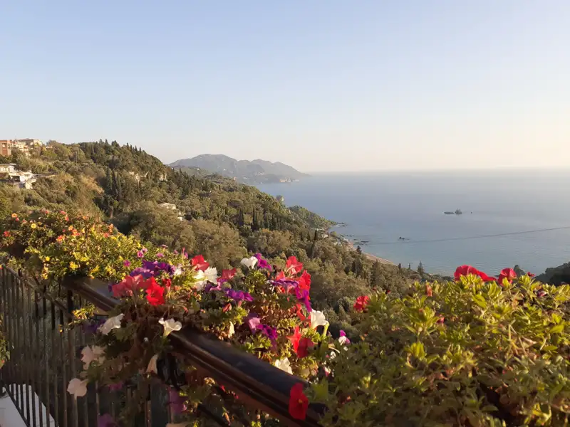 Panoramablick auf die Küste vom Balkon aus, mit Blick auf das Meer und bewachsene Hügel.