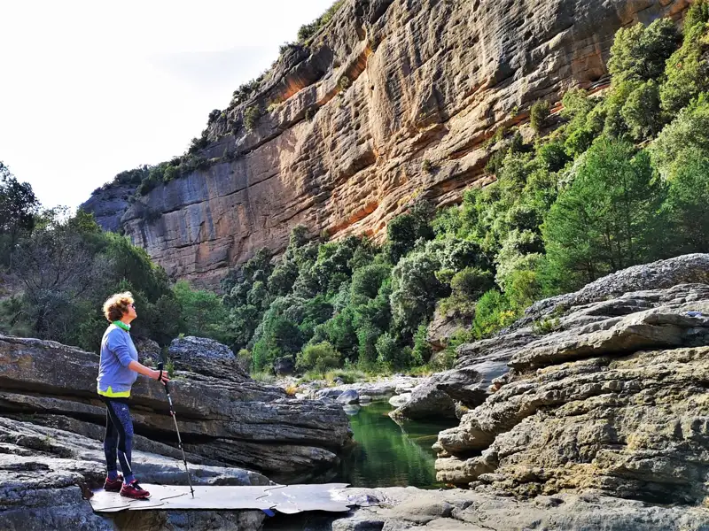 Wanderer in einer Schlucht mit Fluss und hohen Felswänden.