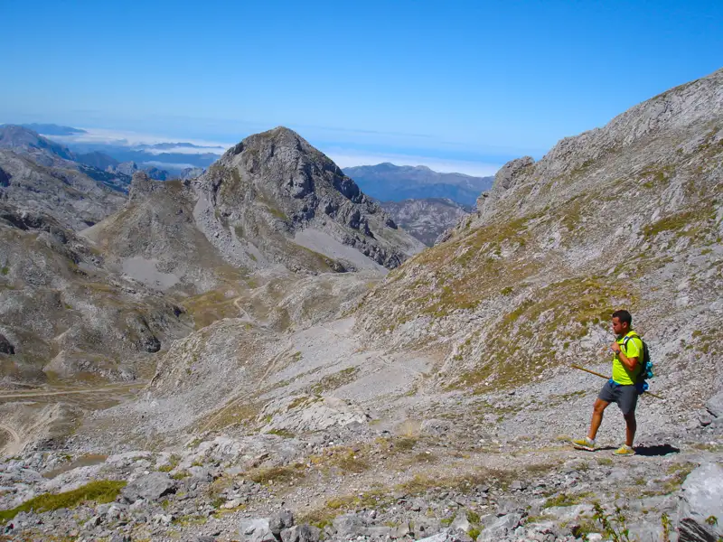 Wanderer auf einem Bergpfad inmitten einer felsigen Landschaft.