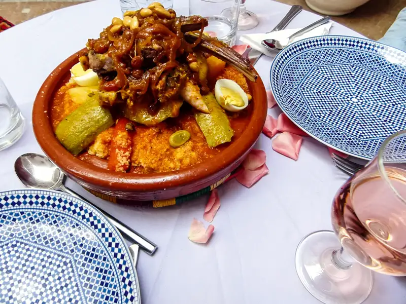 Couscous mit Fleisch, Gemüse und Eiern in einer Terrakotta-Schale.