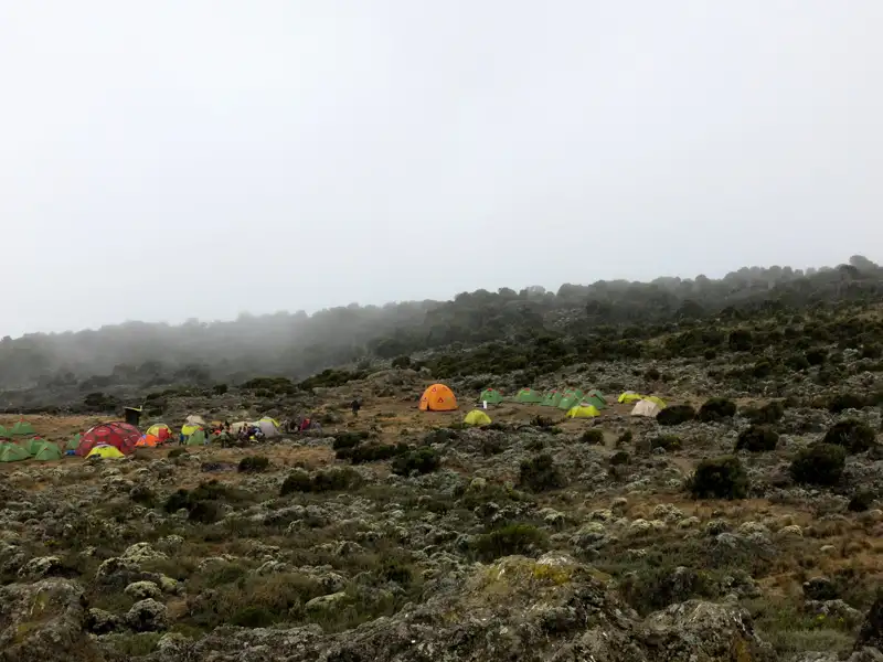 Basislager mit Zelten in nebliger Berglandschaft.