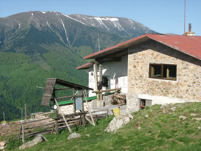 Eine Berghütte in den Bergen mit Blick auf einen schneebedeckten Gipfel.