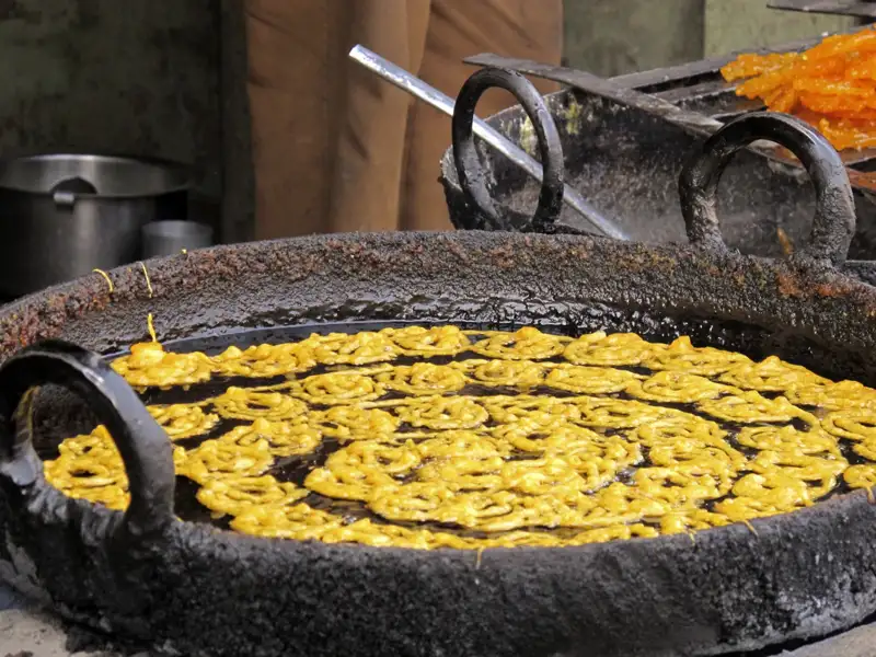 Frittieren von Jalebis in einer großen Pfanne mit heißem Öl.