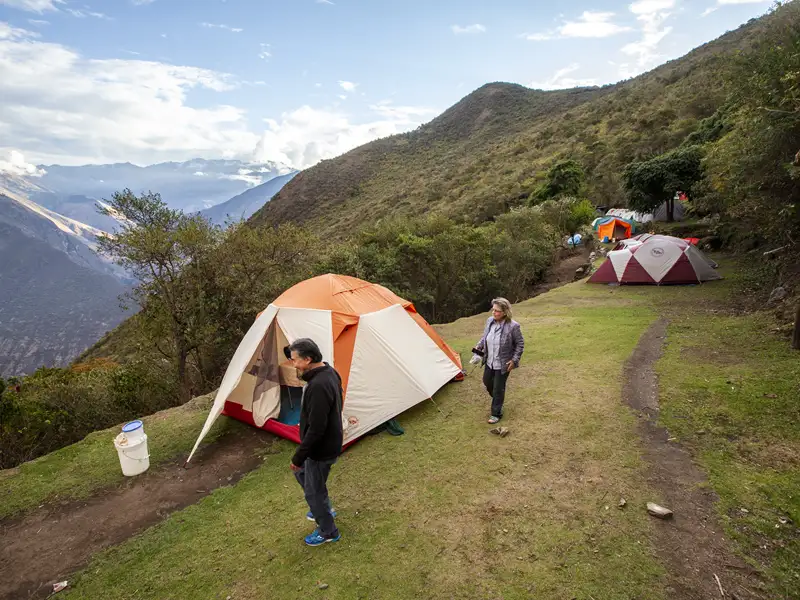 Campingplatz in den Bergen mit mehreren Zelten und Reisenden.